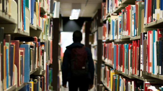 A student walking through bookshelves