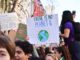 A poster calling for climate action is held by a protester