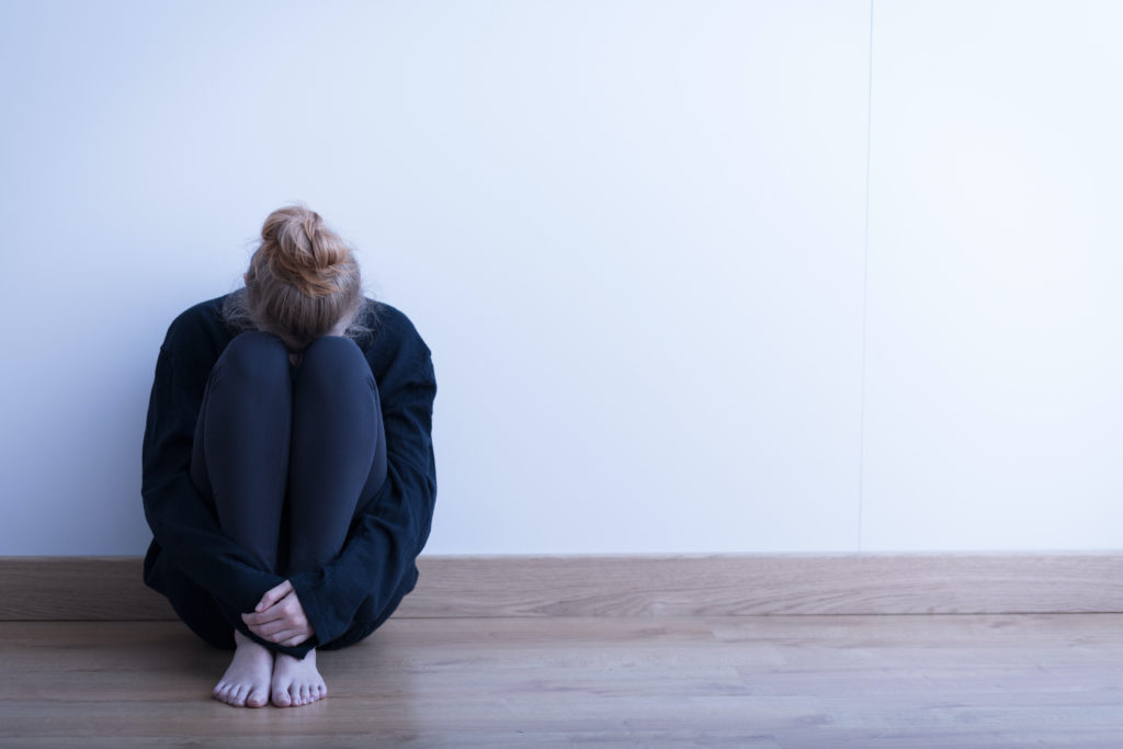 Woman sitting curled up on the ground