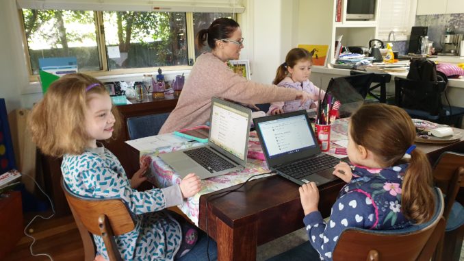20200504_091547 Mother working at home with three kids, all with laptops.