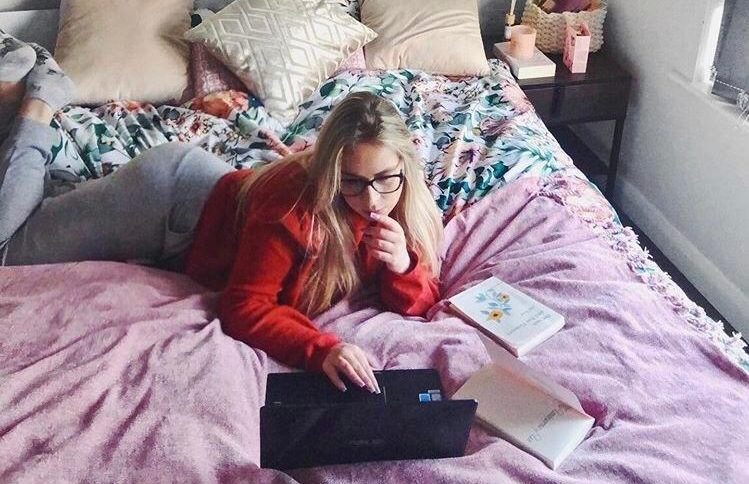 Young girl using her laptop on bed