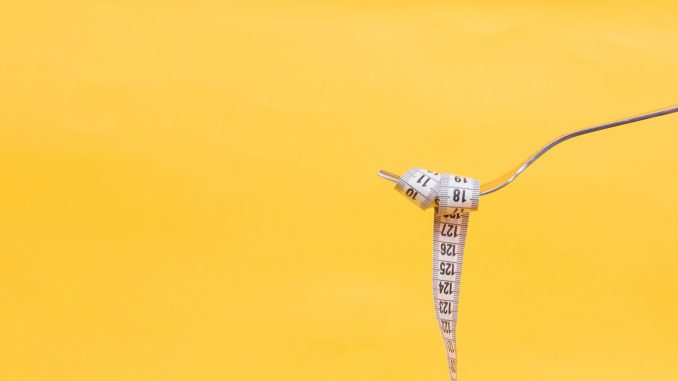 A yellow background with a fork and a measurement tape