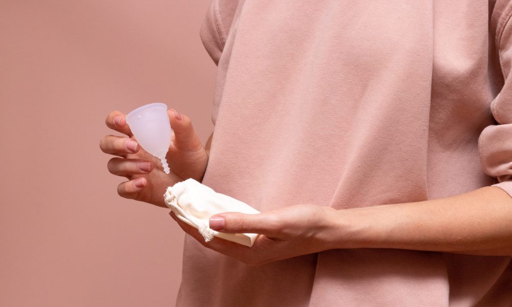 woman holding menstrual cup and pads