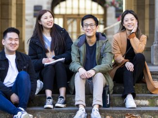 Chinese international students sit fornt the arch of taching building university