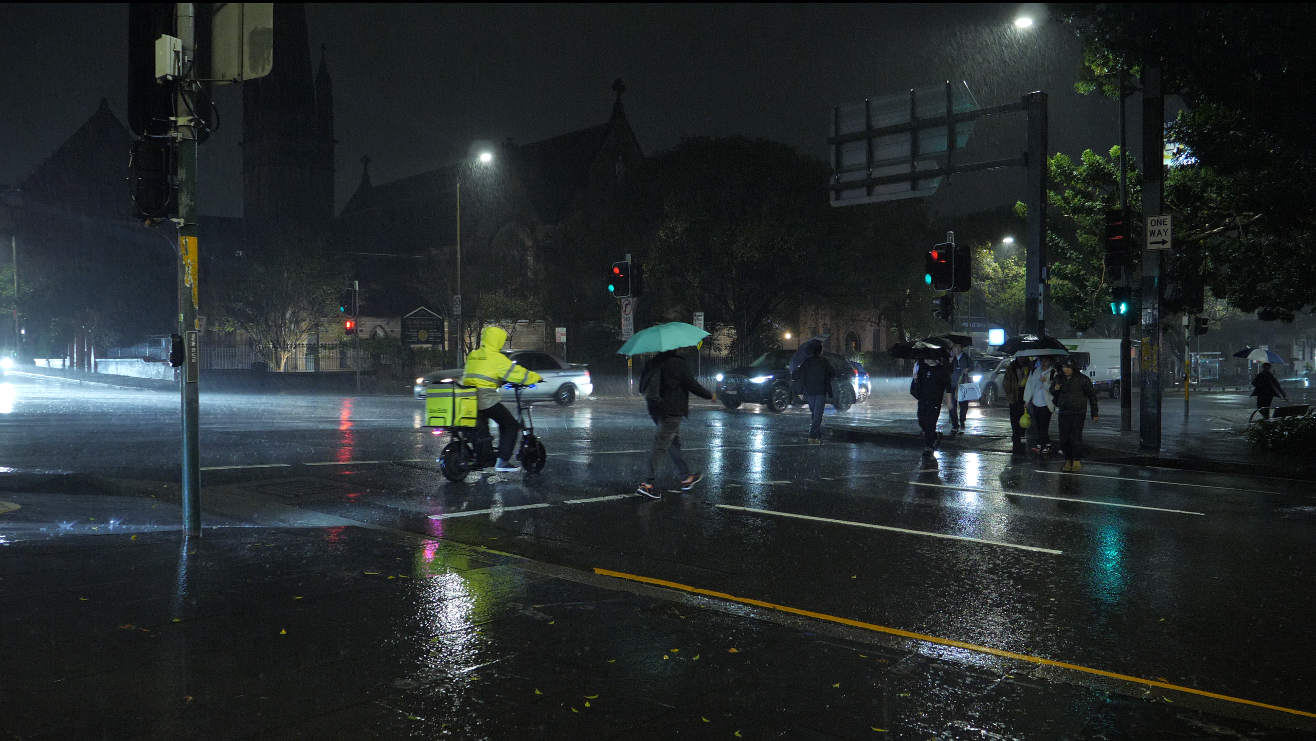 A delivery rider goes against traffic without a helmet in heavy rain. // Photo by Lyn Zhan