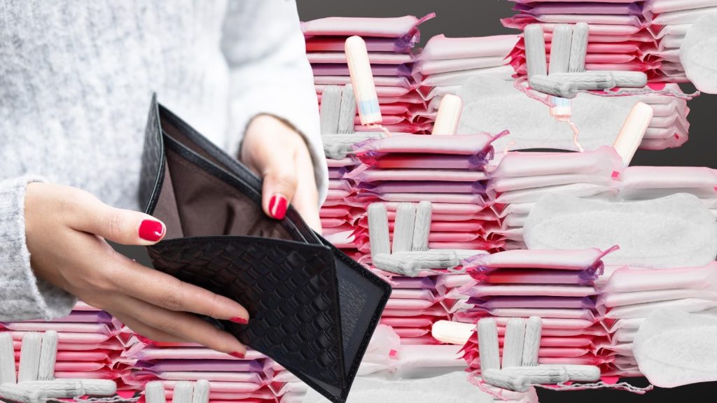 A woman with red-painted nails opens her empty black purse as shelves of menstrual products fill the back of her.