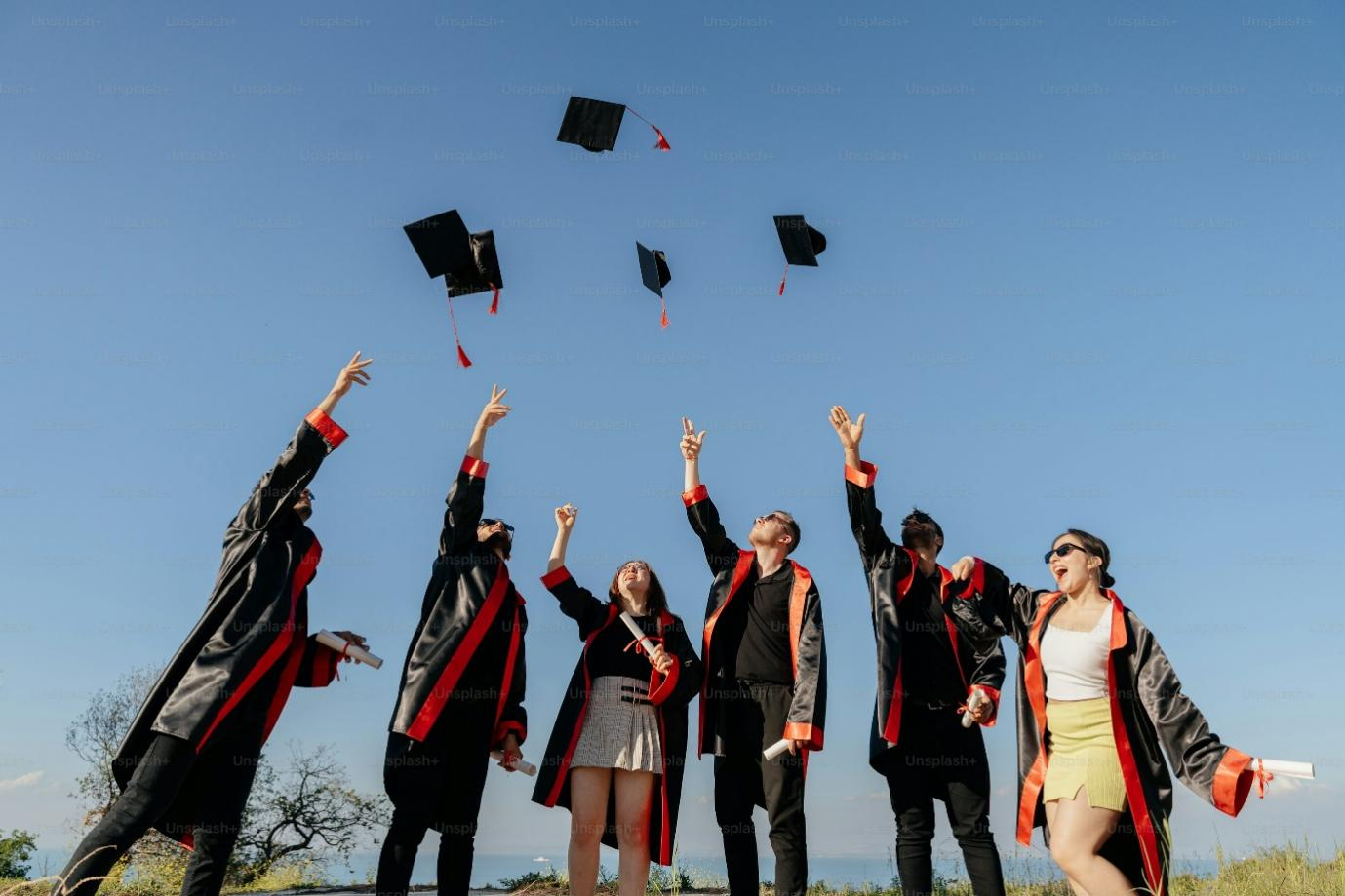A group of students are tossing their graduation caps.