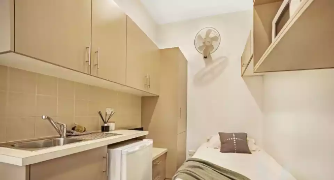 Very crowded student dormitory with the kitchen next to the bed